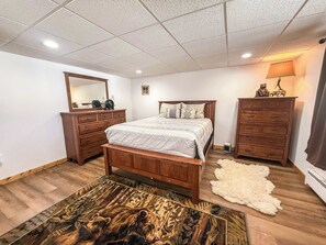 A bedroom with a wooden bed, a dresser, a mirror, and a rug. - Alpine Horn #3 ~ Sauna & Close to Powderhorn! (Bessemer)
