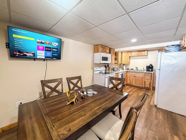 A dining area with a wooden table, chairs, and a TV displaying a streaming service menu.