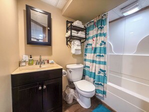 A bathroom with a sink, mirror, toilet, and shower curtain.