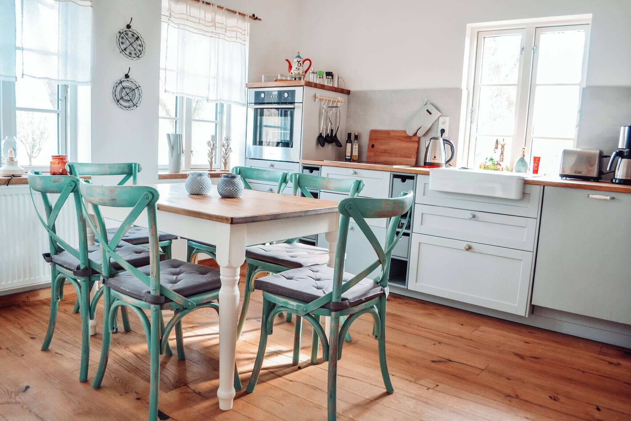 A kitchen with a wooden table and chairs, a stove, and a window.