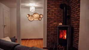 A cozy living room with a fireplace, a sofa, and a wall-mounted decorative piece. - Viltpark Rollerbü Hjortaröd (Tyringe)