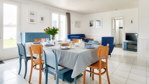 A dining area with a table set for four, blue chairs, and a blue sofa. - House for 10 with garden in Noirmoutier (Noirmoutier-en-l´Ile)