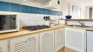 A compact kitchen with a gas stove, white cabinets, a blue-tiled backsplash, and a built-in dishwasher. - House for 10 with garden in Noirmoutier (Noirmoutier-en-l´Ile)