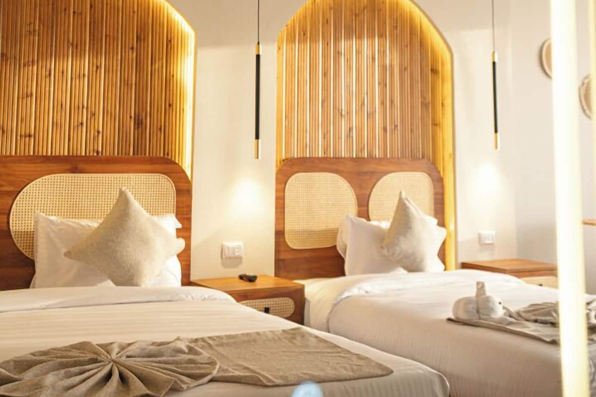 Habitació d'hotel amb dos llits, amb capçaleres de fusta i làmpades laterals.