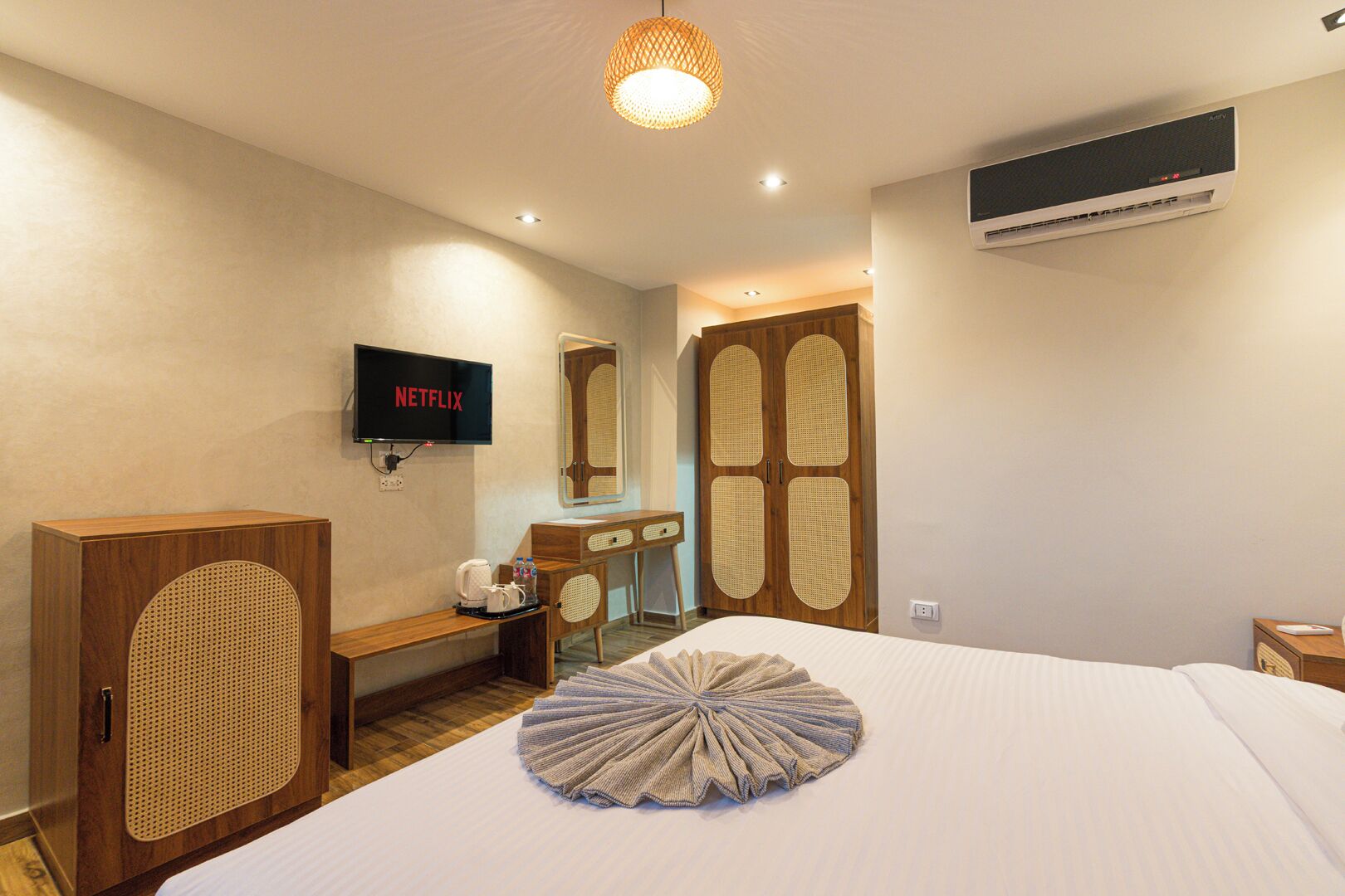 Una habitación de hotel con cama, escritorio, televisión y aire acondicionado.