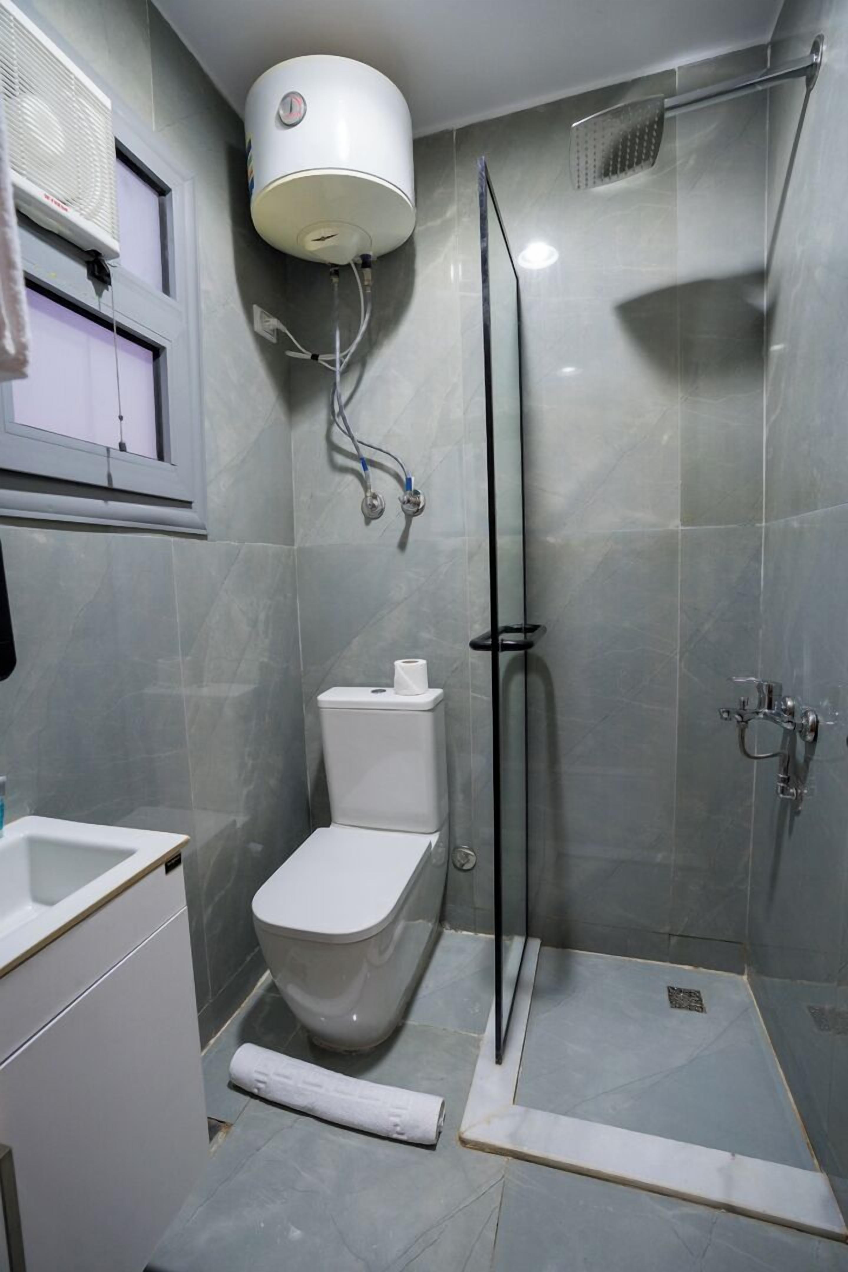 Un baño con inodoro, cabina de ducha y calentador de pared.