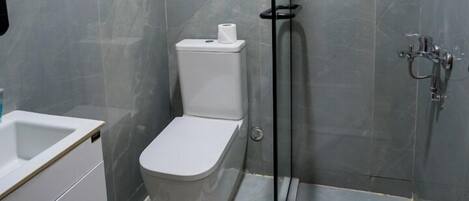 Un baño con inodoro, cabina de ducha y calentador de pared.