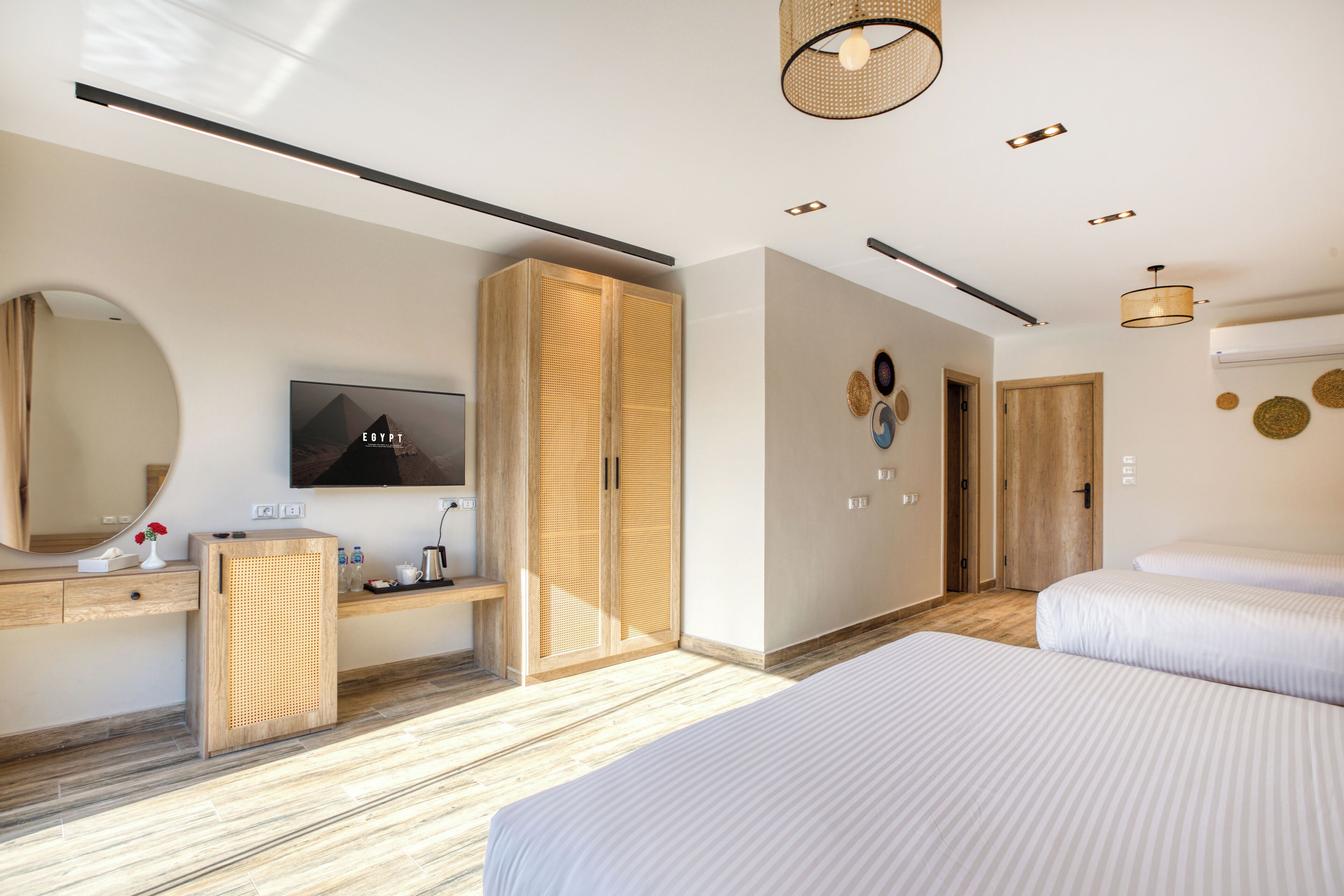 A modern hotel room with a large bed, a TV, a wardrobe, and a bathroom.