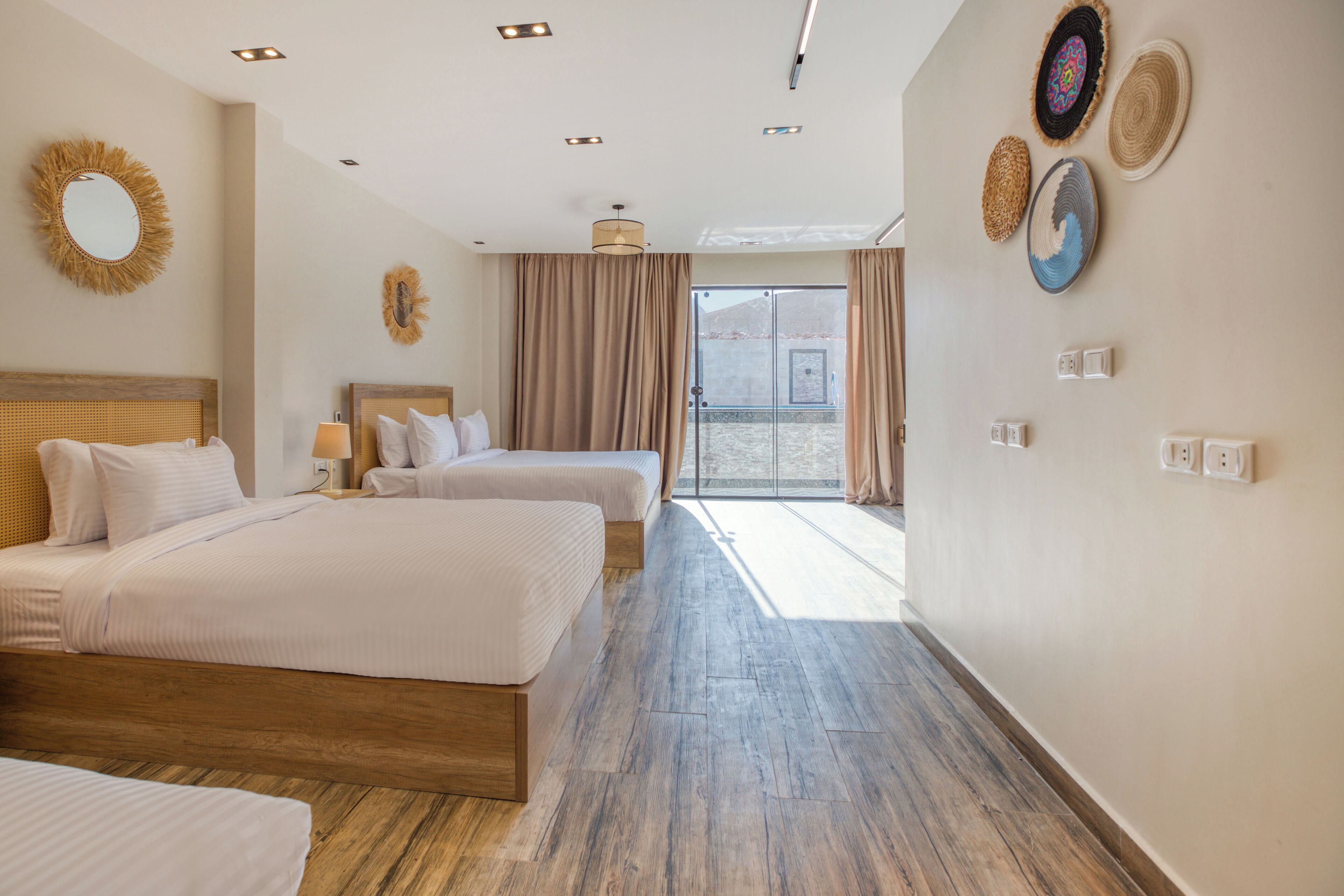 A hotel room with two beds, a large window, and a view of the outside.
