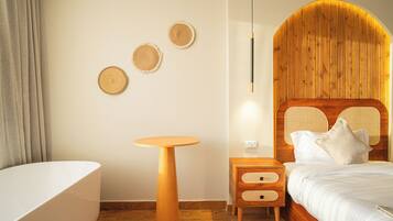 Ein modernes Schlafzimmer mit einem Holz-Kopfende, einem runden Nachttisch aus Holz, einem runden Holztisch und einer großen weißen Badewanne.