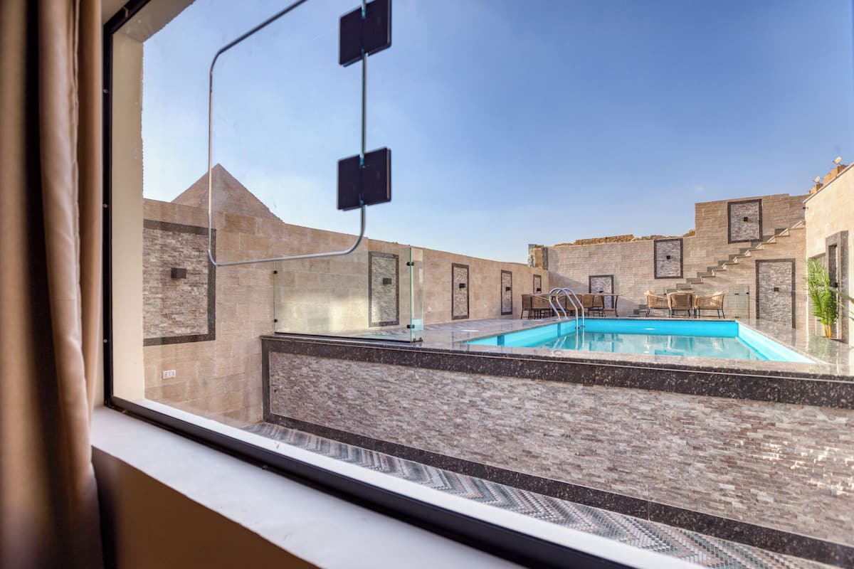 Zona de piscina amb una vista clara de la piscina, una cadira i una escala que condueix a un edifici.