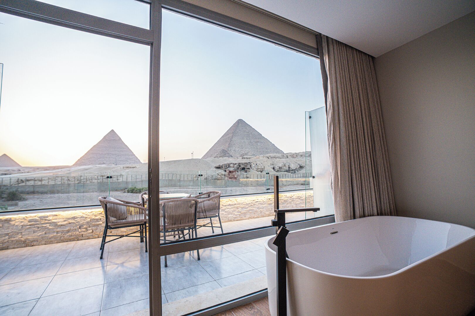 Una habitación de hotel con un ventanal que ofrece vistas a las pirámides.