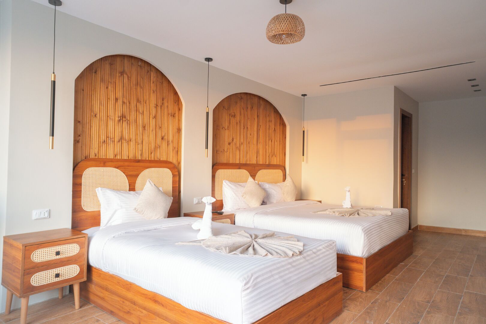 Ein Doppelzimmer mit zwei Betten, Holz-Kopfteilen und einem kleinen Nachttisch.