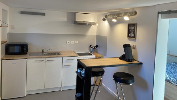 A compact kitchen with white cabinets, a microwave, a coffee machine, and a small bar area with stools. - Apartment 2 people -Poncin (Poncin)