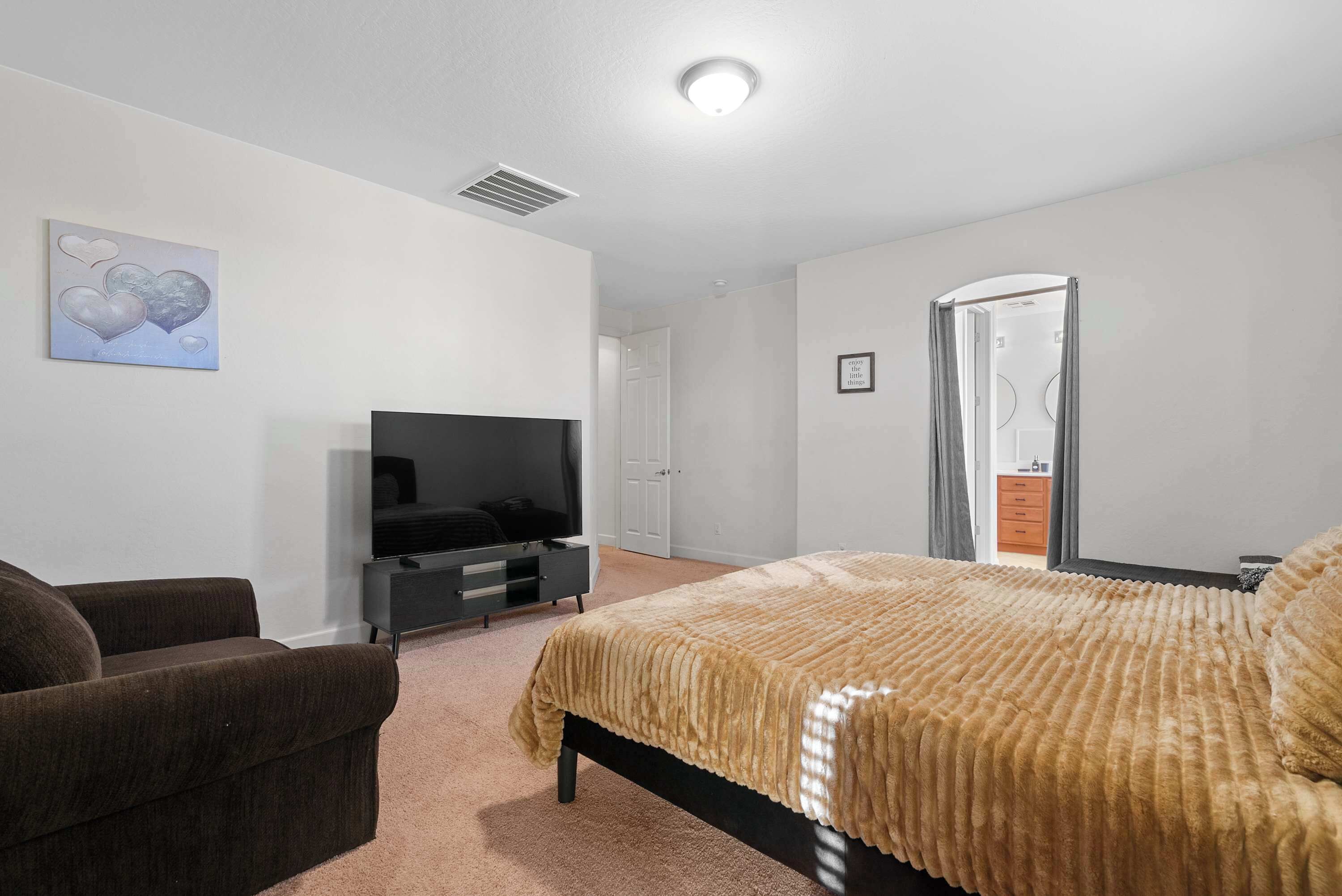 A bedroom with a bed, a TV, a sofa, and a door.