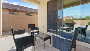 A patio with wicker furniture and a glass door leading to a covered area. - Family Friendly  w/ Badminton | Goodyear Park (Goodyear)