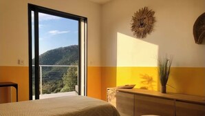 A bedroom with two beds, a view of a mountain, a sunburst wall decoration, and a plant on a dresser. - Villa located between sea and mountains (Conca)