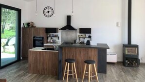 A modern kitchen with a central island, bar stools, a built-in stove, and pendant lighting. - Villa located between sea and mountains (Conca)