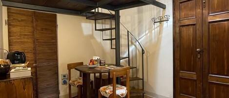 Un espace repas comprenant une table et des chaises, un escalier menant à un niveau supérieur et une porte en bois.