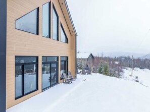 Un edificio moderno con ampie finestre e una zona esterna coperta con sedie.