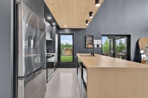 A modern kitchen with a stainless steel refrigerator, wooden countertop, and a view of the outdoor area.