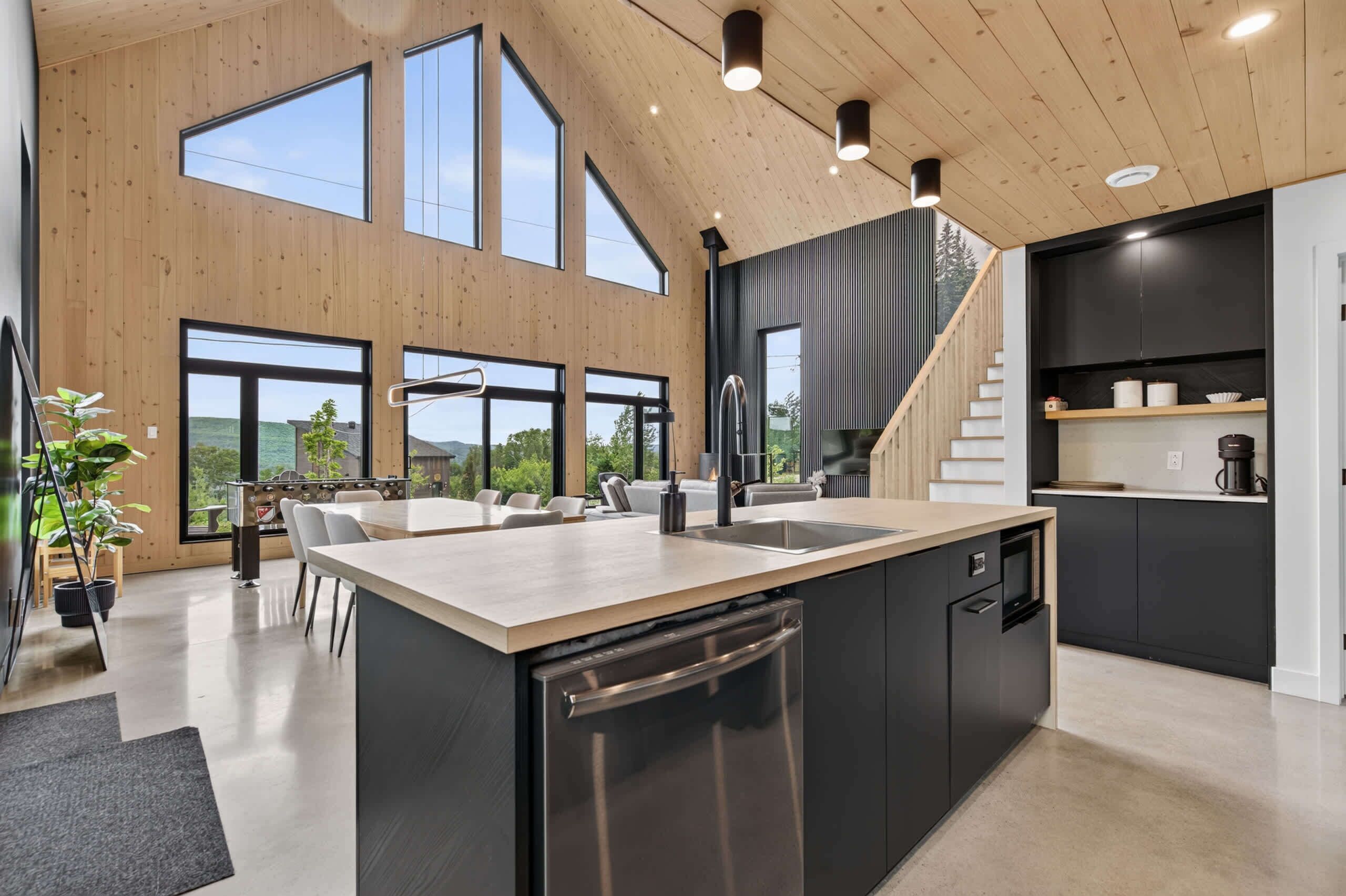 Een moderne keuken met een groot eiland, ingebouwde apparatuur en een trap naar een hoger niveau.