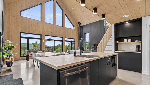 A modern kitchen with a large island, built-in appliances, and a staircase leading to an upper level.