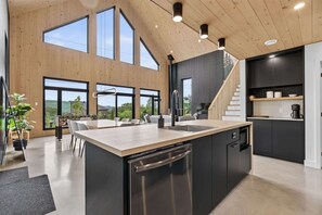 A modern kitchen with a large island, built-in appliances, and a staircase leading to an upper level.