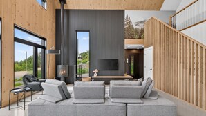 A modern living room with a large gray sectional sofa, a flat-screen TV, and a fireplace.