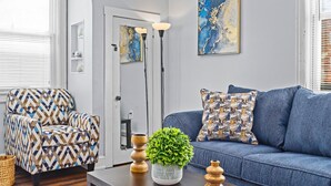 A modern living room with a patterned armchair, a blue sofa, and decorative pillows.