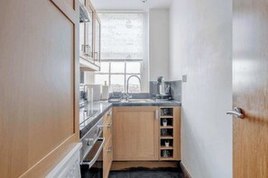 A compact kitchen with wooden cabinets, a built-in oven, and a window providing natural light.
