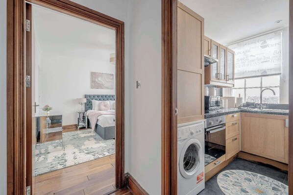 Eine kompakte Wohnung mit Schlafzimmer, Küchenzeile und Blick auf die Stadt.