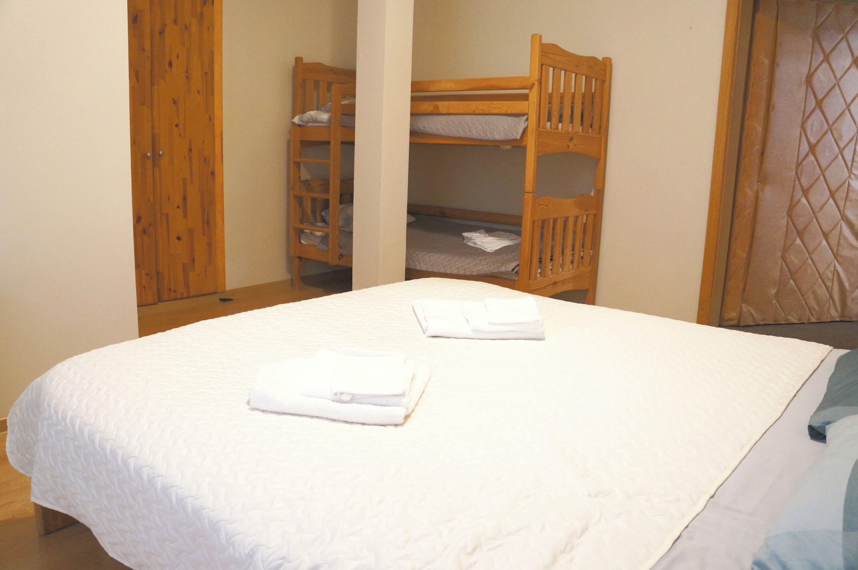A single bed with white bedding and two neatly folded towels.