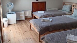 Slaapkamer met twee bedden, dakraam, radiator, ventilator en houten vloer.