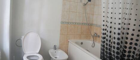 A bathroom with a toilet, bidet, and bathtub.