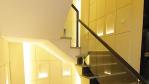 A modern staircase with glass railings and a geometric wall design. - Treebo Paarth Grand (Haridwar)