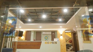 A reception area with a wooden ceiling, glass walls, and a reception desk labeled "RECEPTION". - Treebo Paarth Grand (Haridwar)