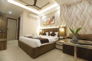 A modern hotel room with a large bed, bedside tables, a desk, and a ceiling fan. - Treebo Paarth Grand (Haridwar)