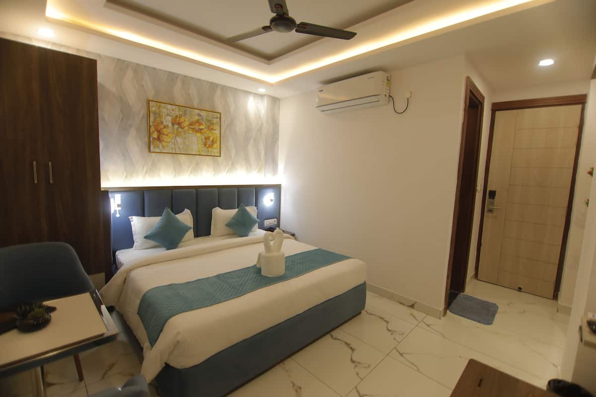 A modern hotel room with a large bed, a desk, a chair, and a ceiling fan.