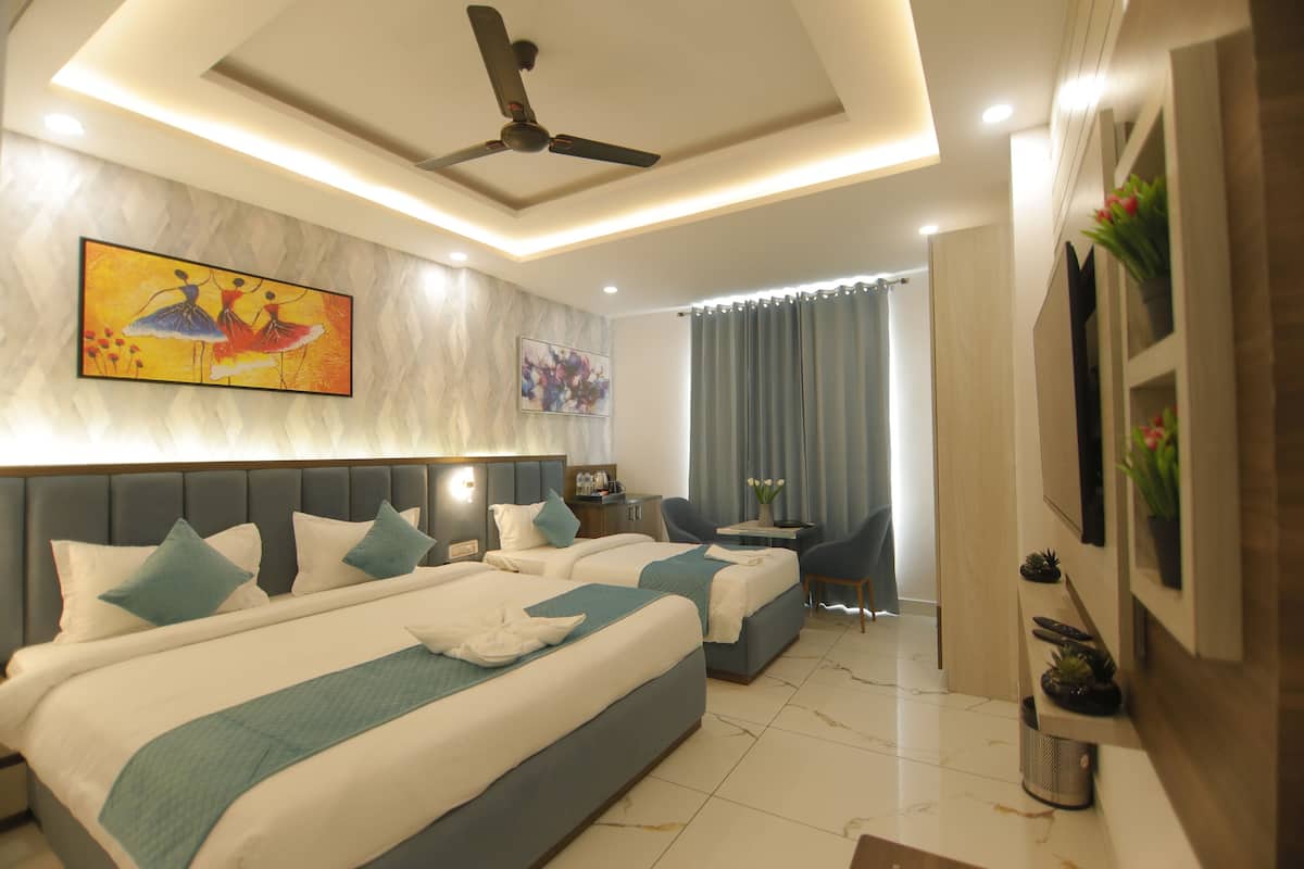 A hotel room with two beds, a ceiling fan, artwork on the walls, a desk with a chair, and a window with curtains.