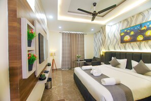 A modern hotel room with a large bed, a ceiling fan, a painting, and a small table with a lamp. - Treebo Paarth Grand (Haridwar)