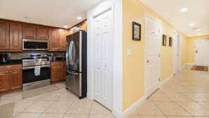 A kitchen with wooden cabinets, stainless steel appliances, and a tiled floor.