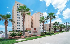 A hotel with a sign indicating private residential condominiums, palm trees, and a clear blue sky.