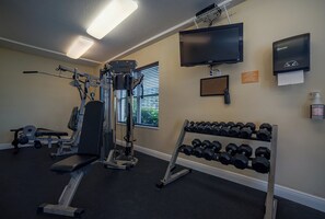 A gym with exercise equipment, a TV, and a wall-mounted hand sanitizer dispenser.