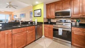 A modern kitchen with wooden cabinets, a stainless steel oven, and a microwave.
