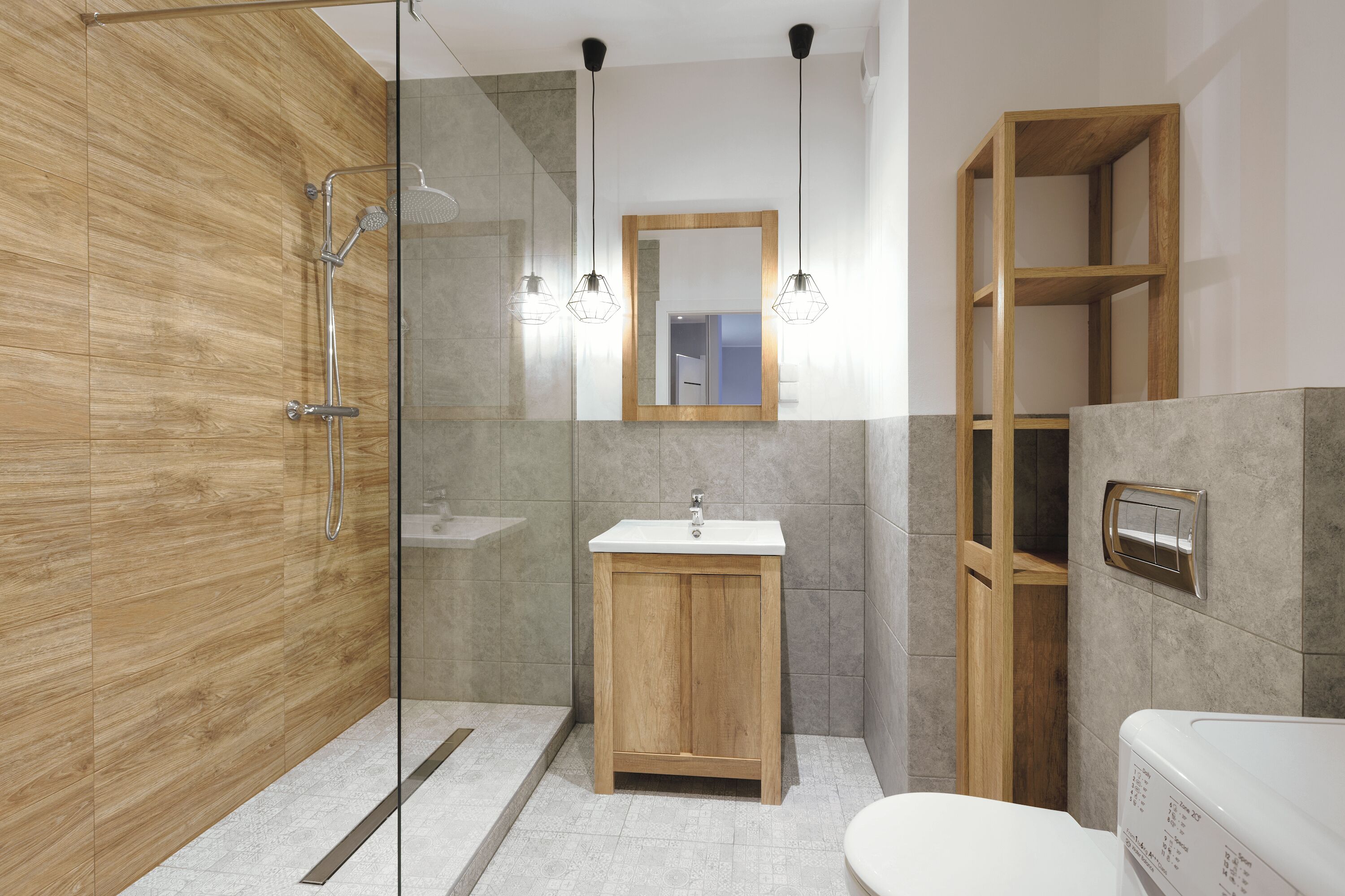 Ein modernes Badezimmer mit einer Duschkabine, einem Holzkosmetikschrank, einem weißen Waschbecken und einer integrierten Ablage.