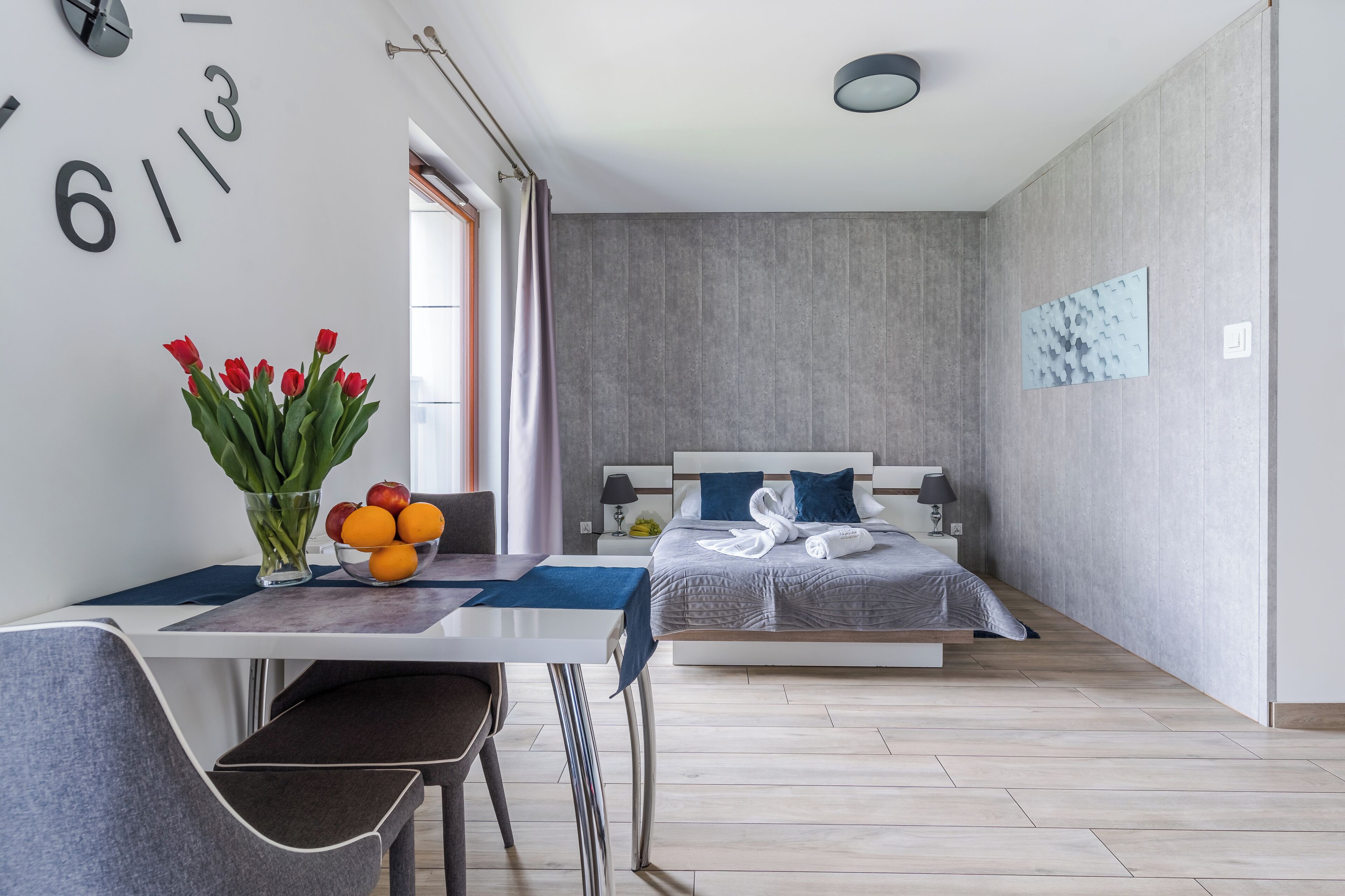 Un dormitorio moderno con cama, mesita de noche y escritorio con silla.