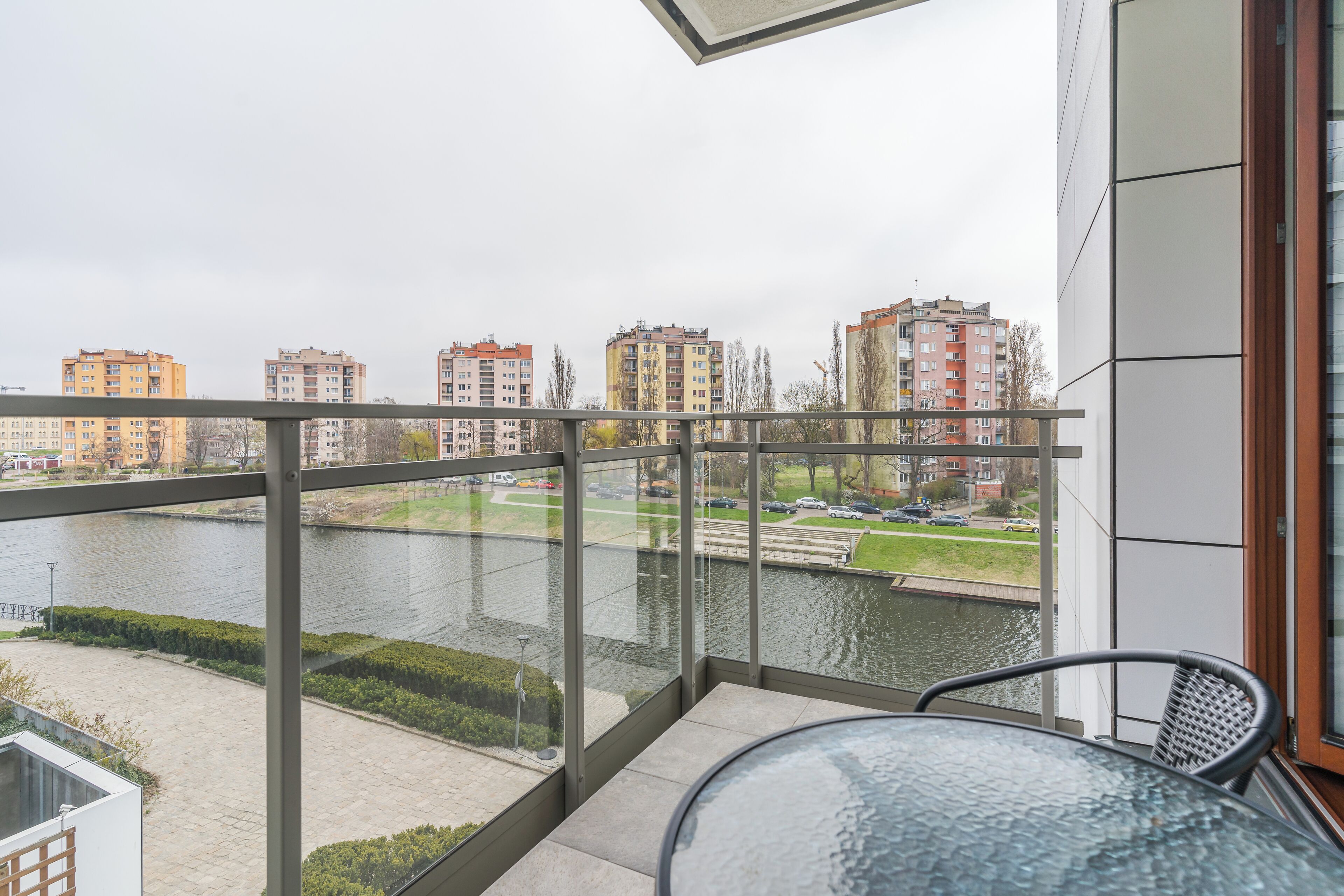 A balcony with a view of a river and buildings across it.