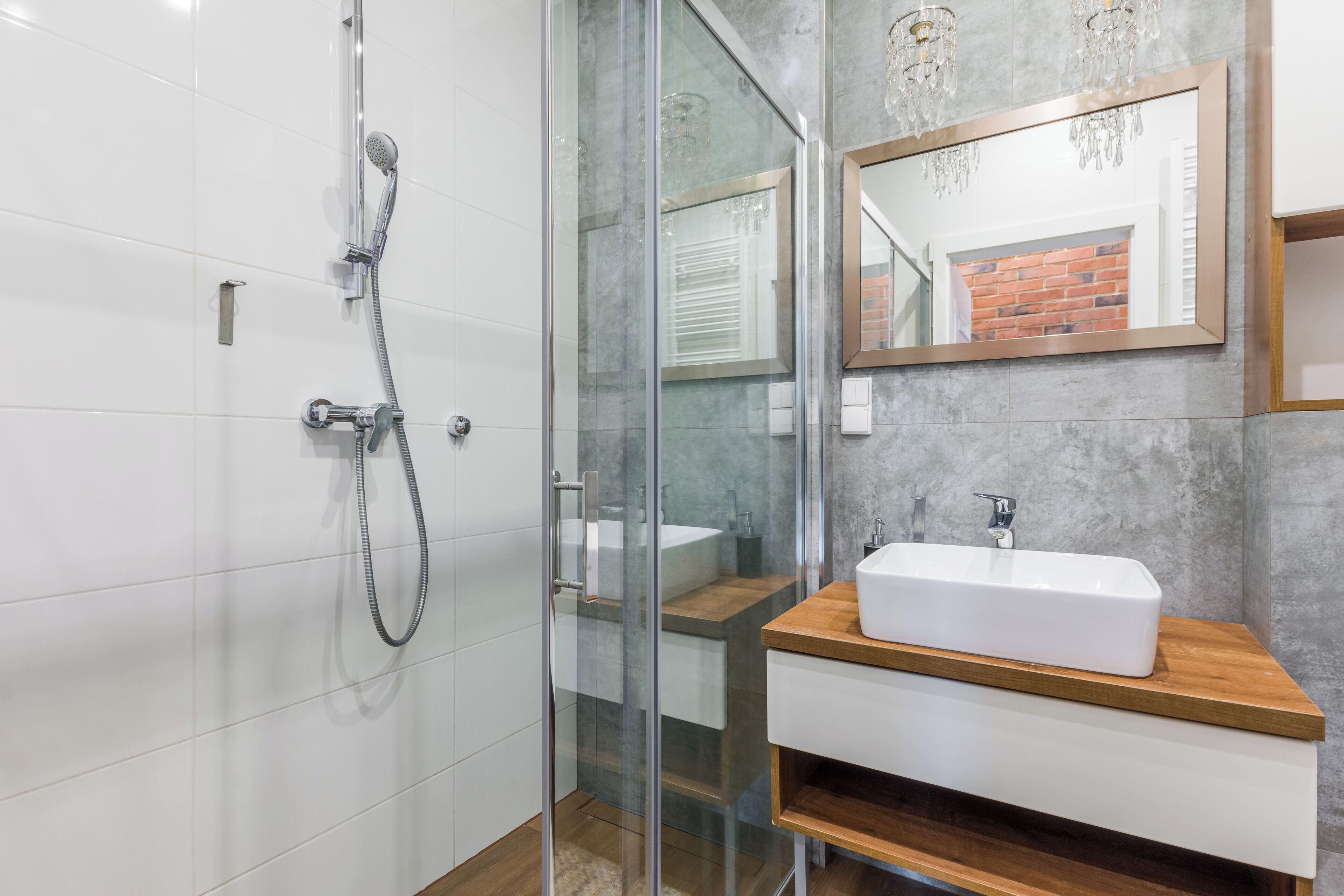 A modern bathroom with a glass-enclosed shower, a white sink, and a mirror with a wooden frame.