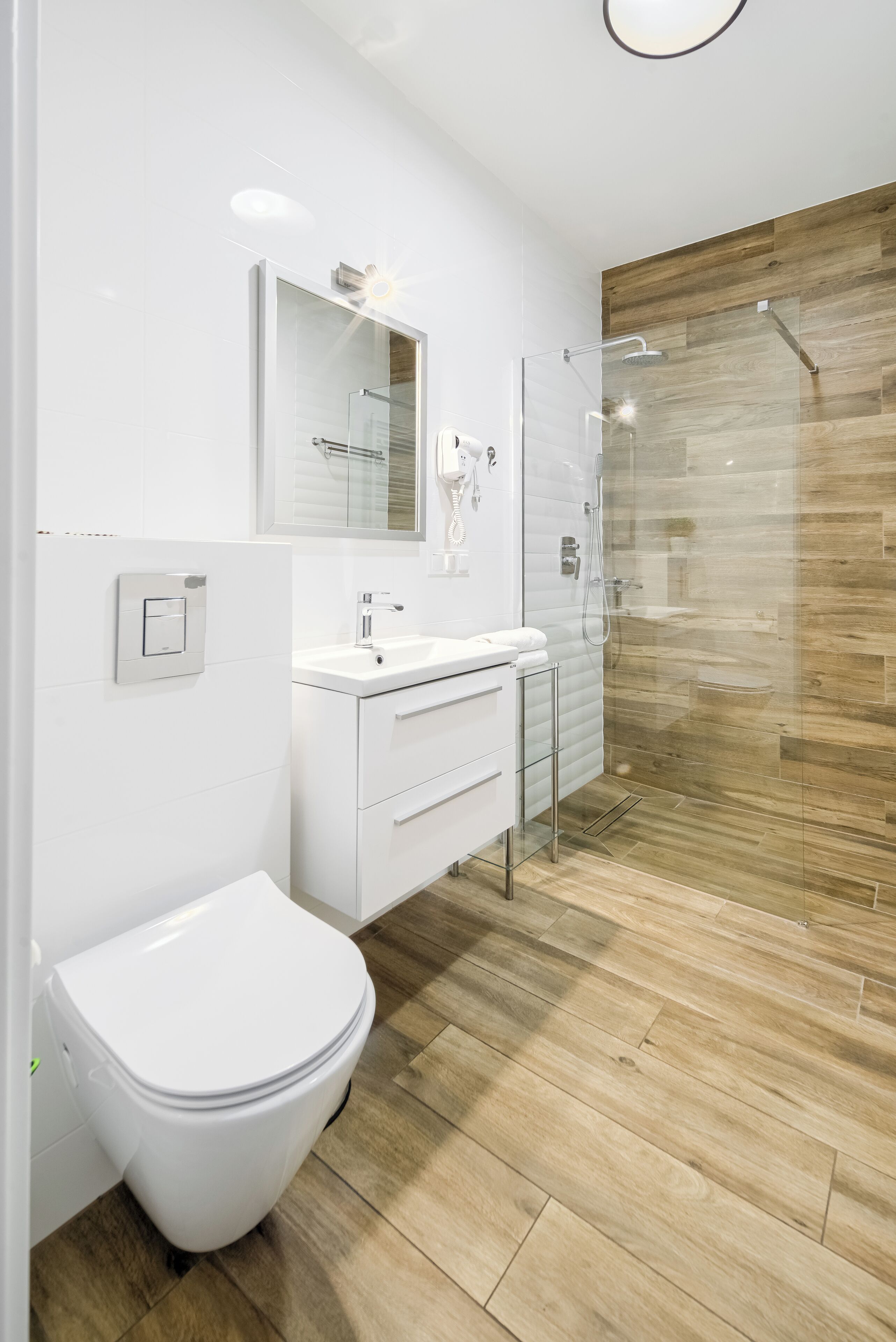 A modern bathroom with a white toilet, a sink, and a glass-enclosed shower.